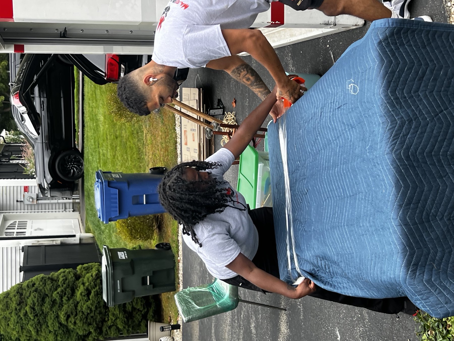 Major Movers crew wrapping furniture in moving blankets and stretch wrap at a driveway