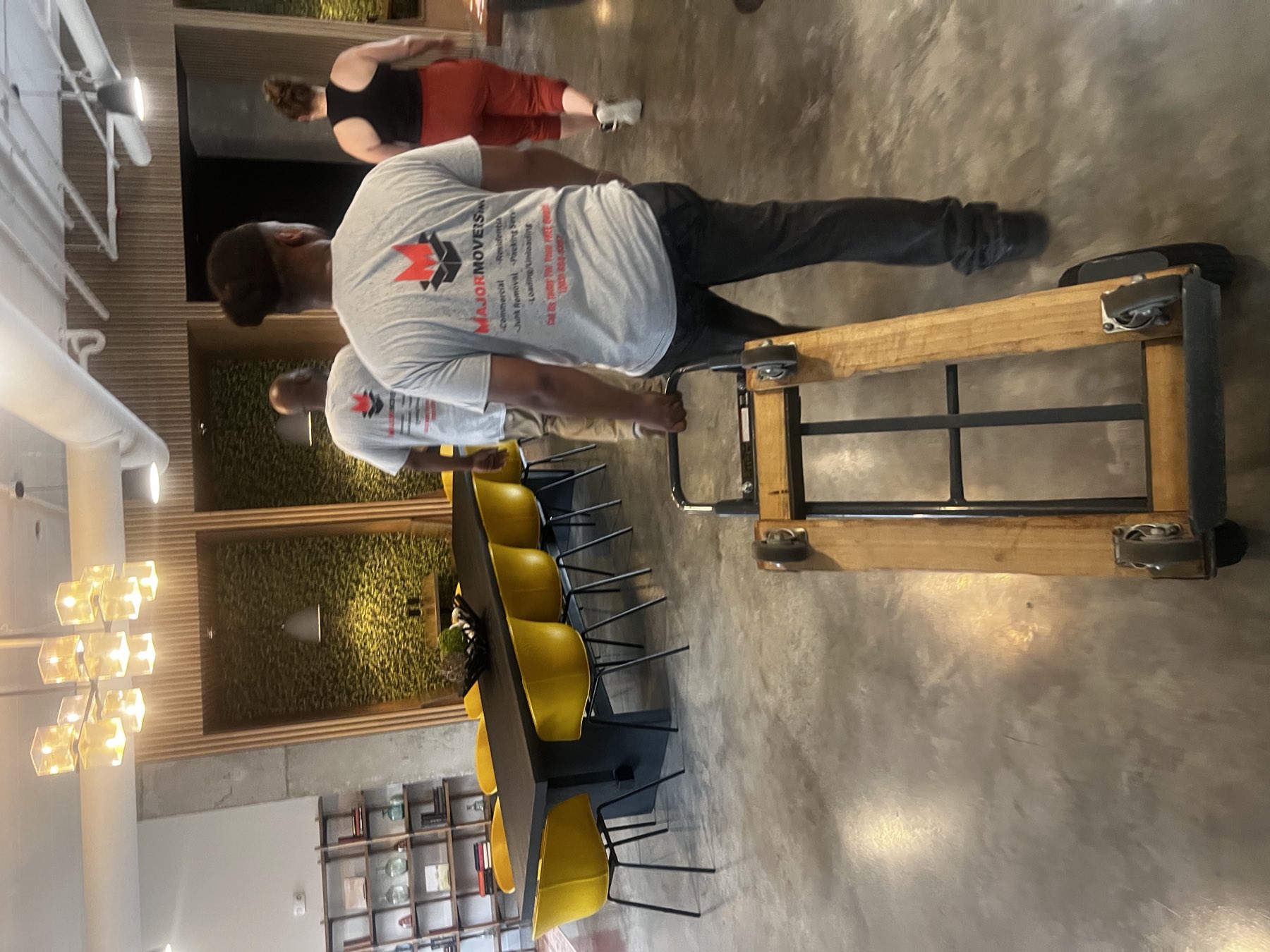 Major Movers crew moving furniture through an office with a four-wheel dolly