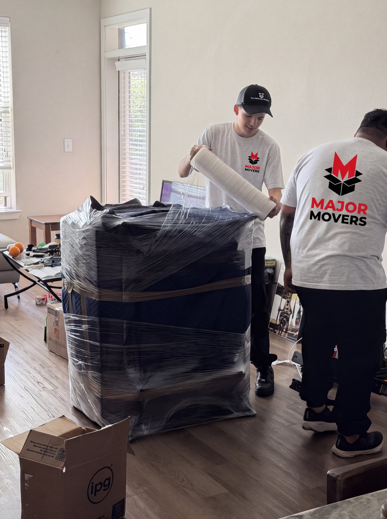 A stacked load of furniture being stretch-wrapped in a living room