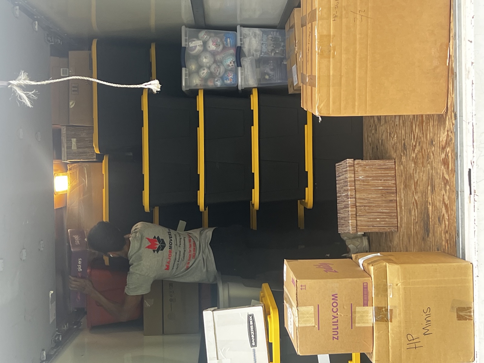 Major Movers worker arranging packed bins and boxes inside a moving truck