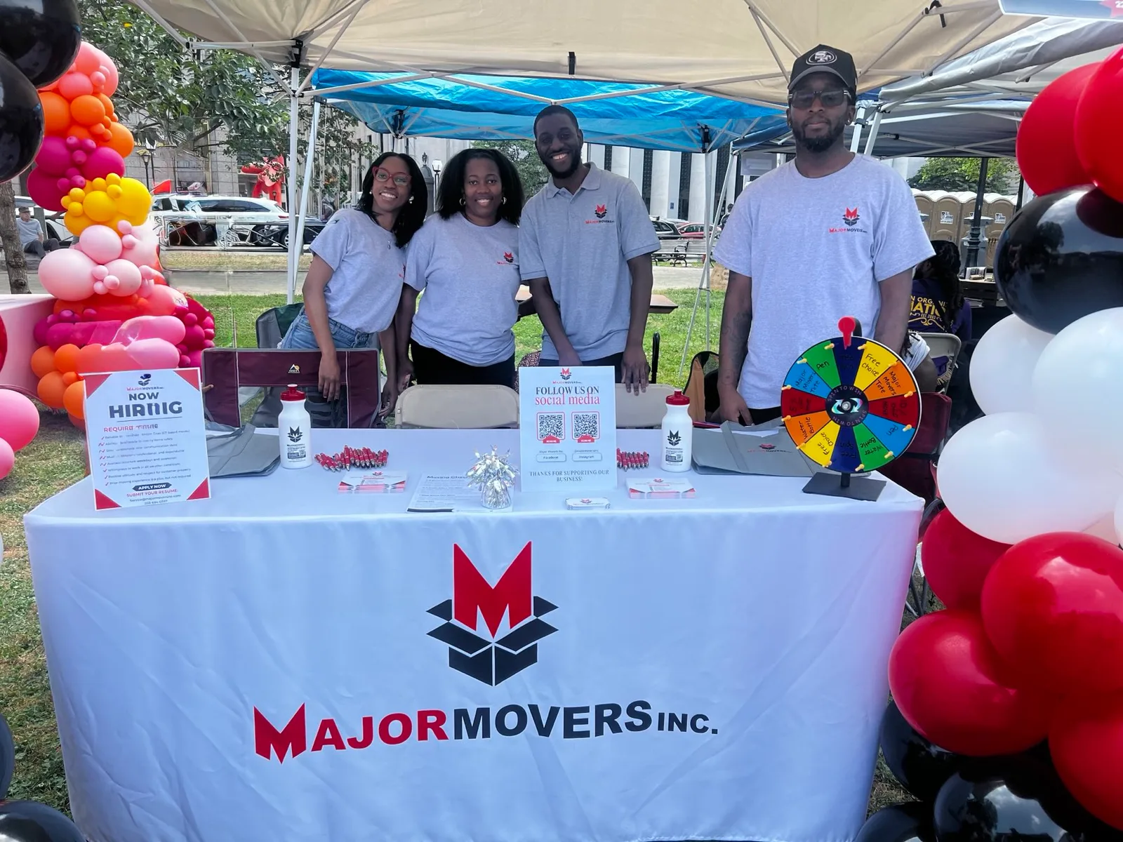 The Major Movers team behind a branded table at a community event