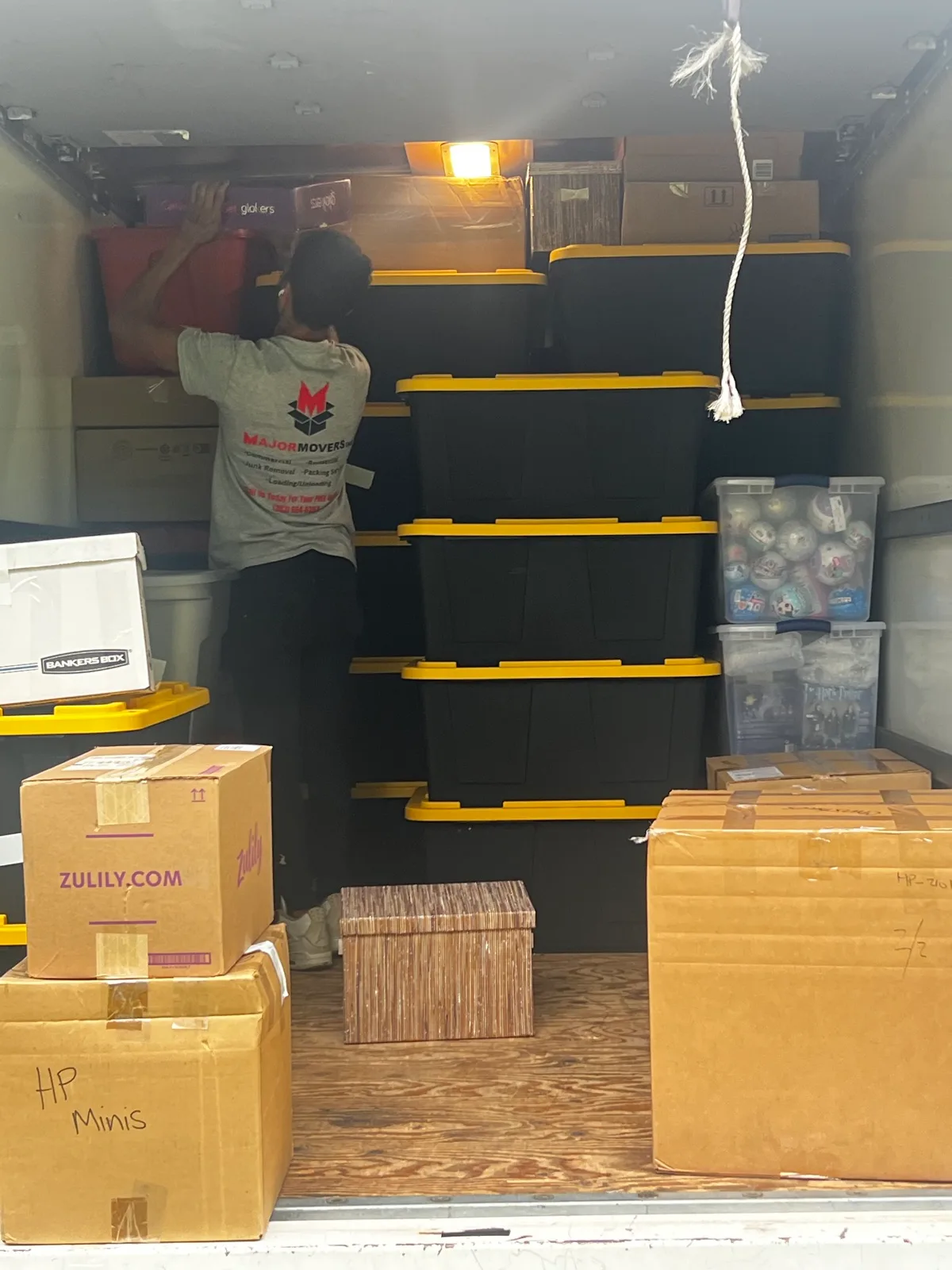 Major Movers worker arranging packed bins and boxes inside a moving truck